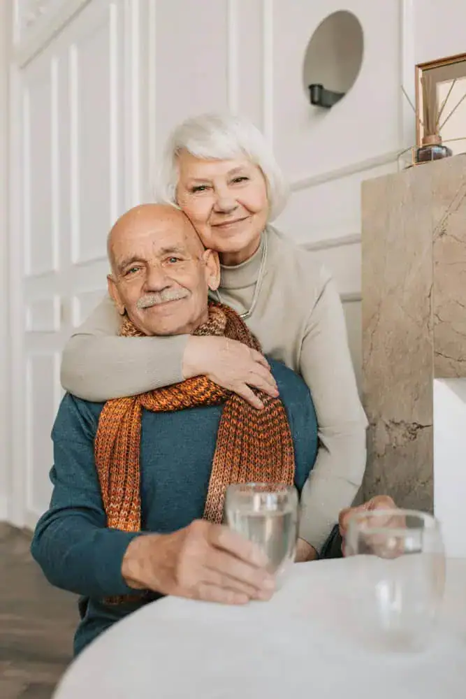Adultos mayores abrazados tomando agua. - Distribuidores de pañales para adultos